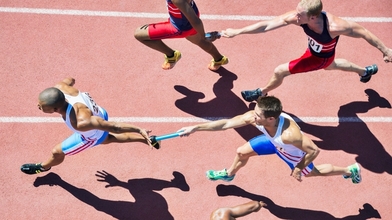 Relay runners passing batons on track